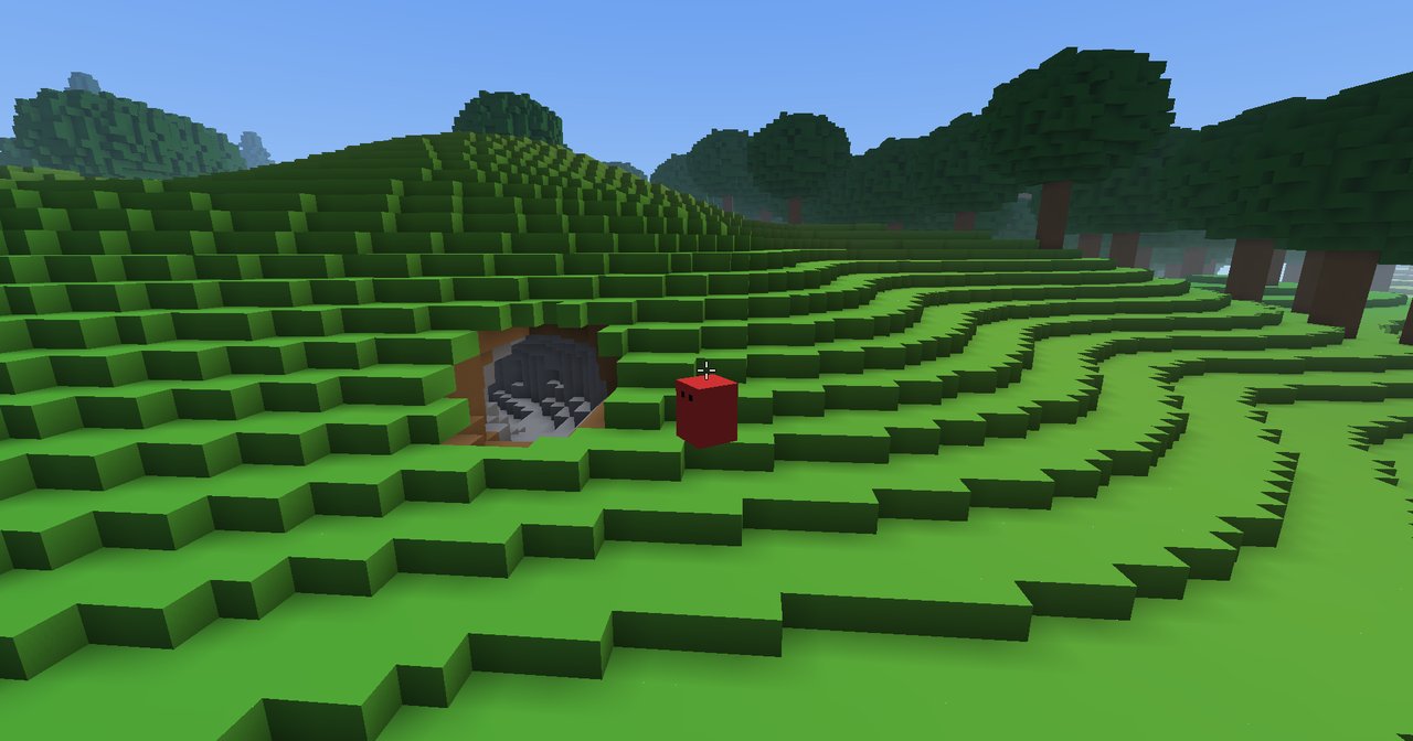 A cave mouth opens in a terraced grassy slope, grey stone visible inside, with the player standing just beside it.