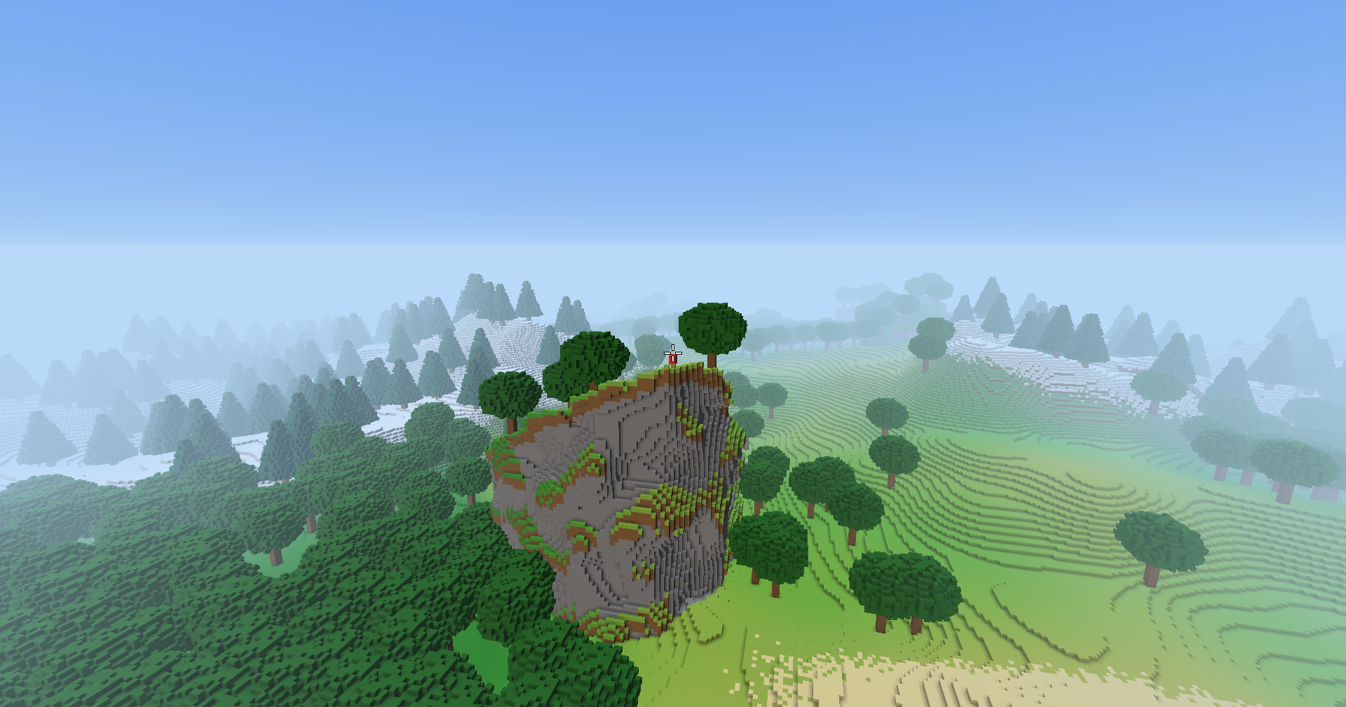 Seen from high above, a grey rock cliff with grass ledges rises out of a forest, trees along its top and the player standing on its edge, with rolling grassland, snowy pine hills and fog beyond.